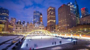 Ice skaters on ice rink in downtToronto with buildings and skyline in background